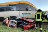 Schwerer Unfall an der B 51: Ein Porsche wurde von einer Regionalbahn erfasst und zwischen Leitplanke und Zug eingeklemmt.