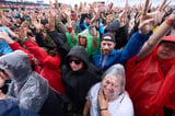 Die Rockfans vor der Hauptbühne des Open-air-Rockfestivals “Rock am Ring“ lassen sich vom Regen die Stimmung nicht verderben.