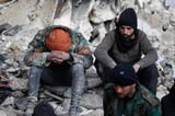 Menschen sitzen auf den Trümmern eingestürzter Gebäude. Die Zahl der Toten im Erdbebengebiet an der türkisch-syrischen Grenze liegt im fünfstelligen Bereich..