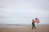 Mit einer US-Flagge in der Hand erinnert ein Reenactor an den D-Day. Am 6. Juni 1944 stürmten fast 160.000 alliierte Soldaten die Strände der Normandie und wendeten das Blatt im Zweiten Weltkrieg.