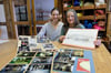 Ingrid Kerber, Vorstandsvorsitzende der Kulturwerkstatt Hiddenhausen (rechts), und Kursleiterin Daniela Perthes engagieren sich seit Jahren ehrenamtlich in der Kulturwerkstatt. Hier zeigen sie alte Fotos und Zeichnungen, die die spannende Geschichte des Vereins und des Hauses dokumentieren.