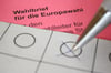 Eine Frau kreuzt einen Wahlzettel für die Briefwahl zum Europäischen Parlament an.