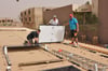 Peter Finke (r.), Albert Guntermann (M.) und Ludger Roggenbuck installieren die PV-Anlage auf dem Dach einer Grundschule.